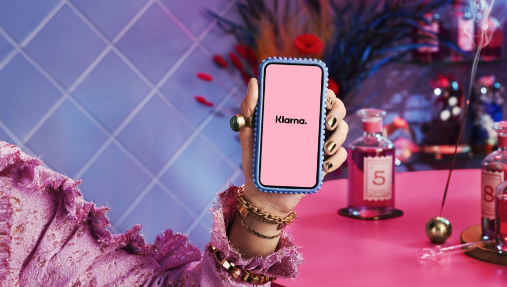 Woman holding a phone showing the Klarna app