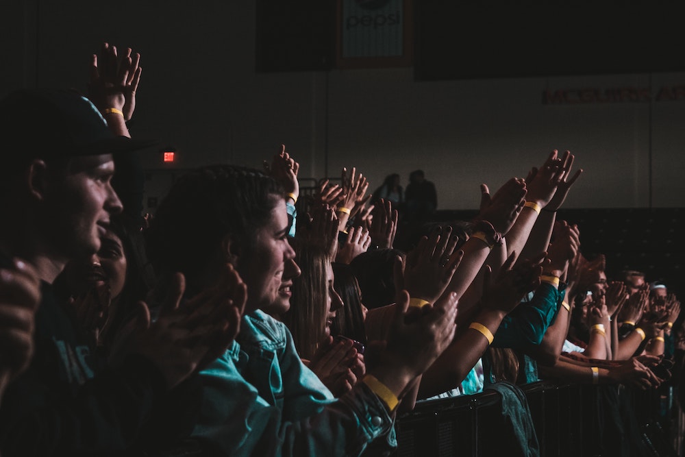 Group of people applauding in a dimly-lit room