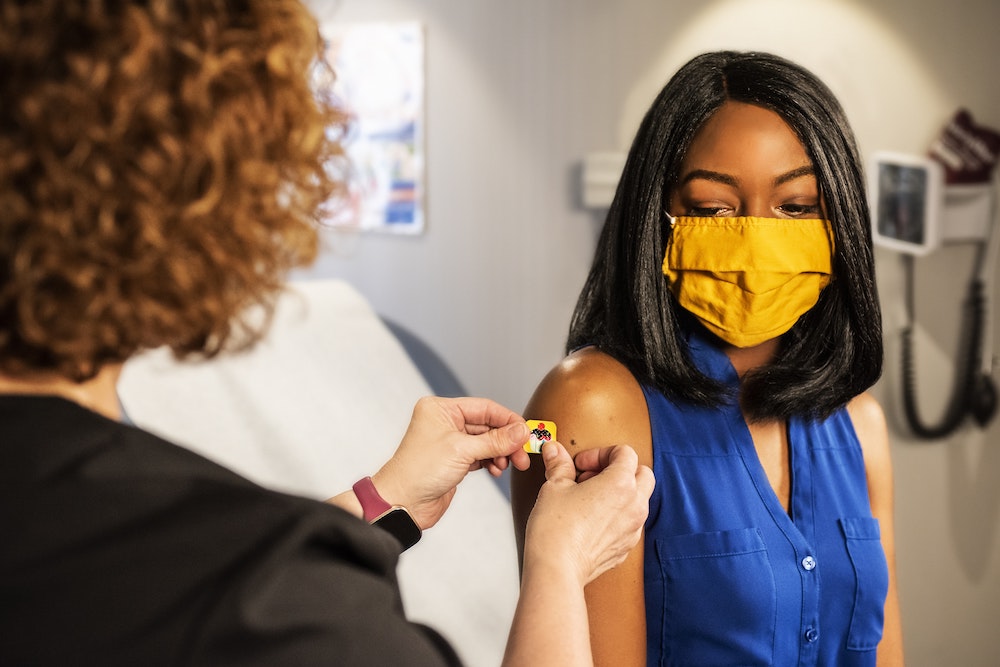 A healthcare business owner placing a band-aid on a patient.