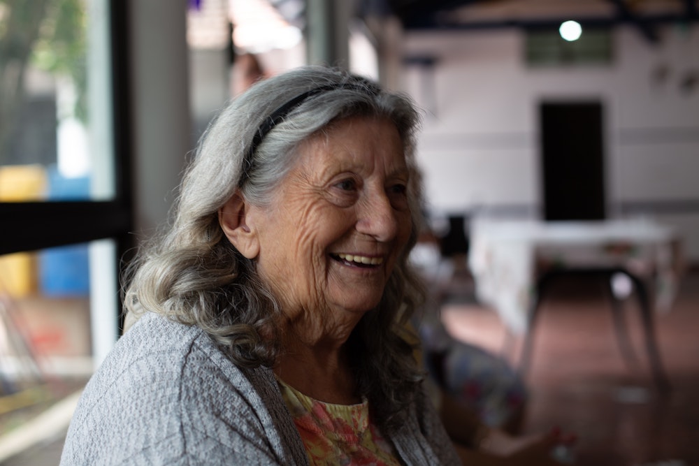 An old woman sitting in a healthcare clinic and smiling.