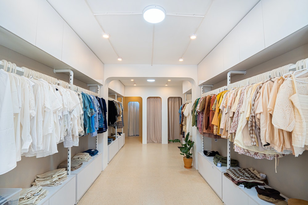 A large changing room with color-coordinated clothes hung on racks along the walls.