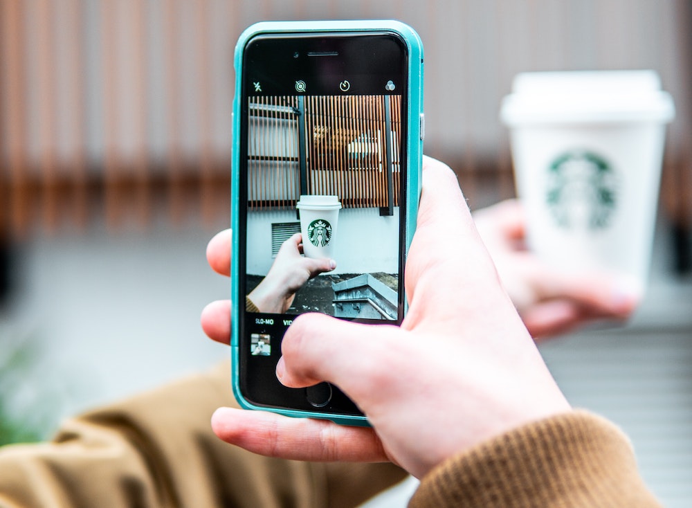 Consumer taking a photo of their Starbucks cup with the brand logo facing the camera