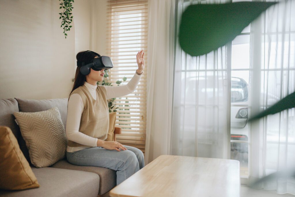 Metaverse : Young woman shopping virtual market with VR glasses in living room.