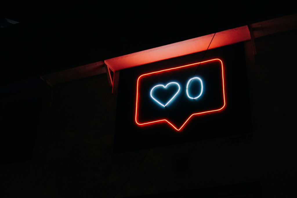 Neon social media like icon showing a heart and the number zero in a dark setting