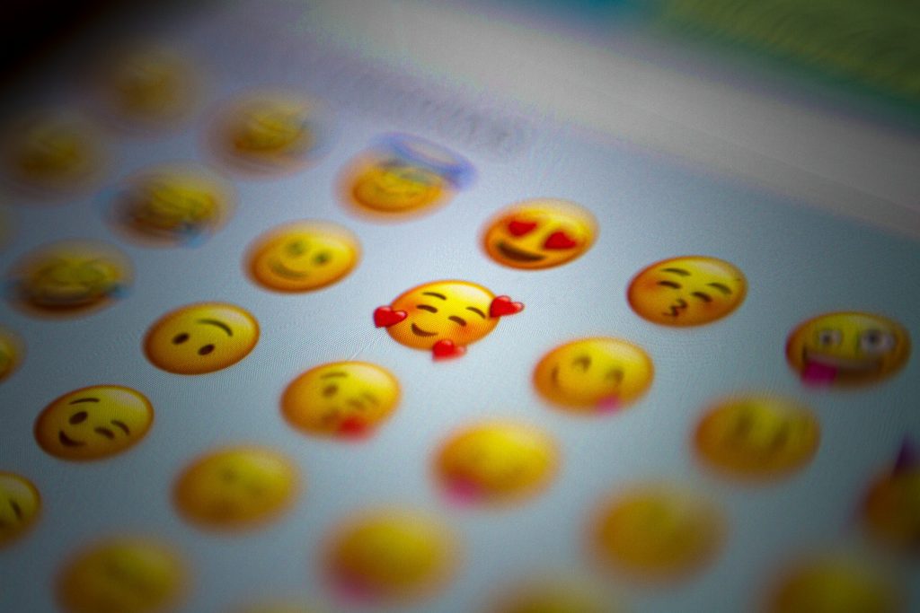 Close-up of emojis on a phone screen with a heart-eyes style emoji in focus.