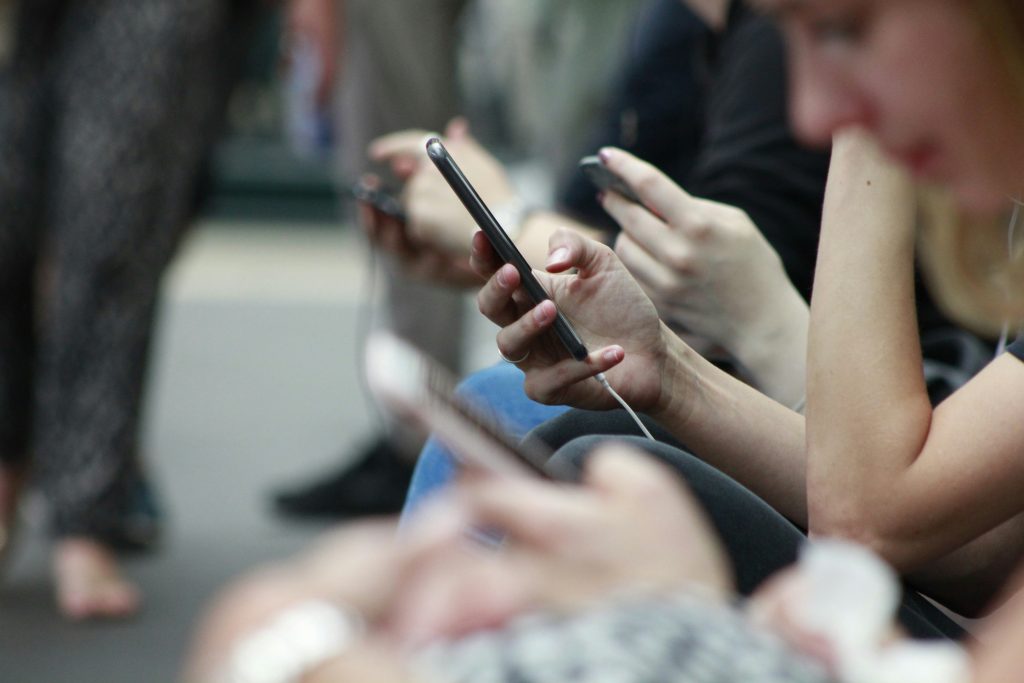 Commuters seated side by side, using smartphones to shop online 