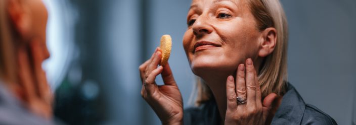 An older women applies skincare products to her face