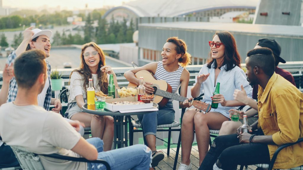 A group of young diners sharing casual food and drinks on a rooftop restaurant