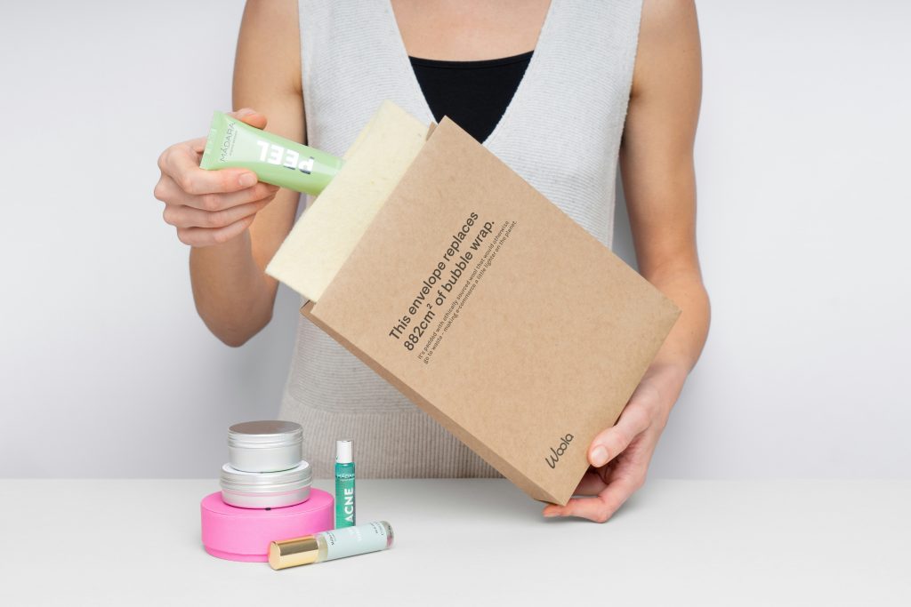 woman placing skincare product into sustainable packaging 