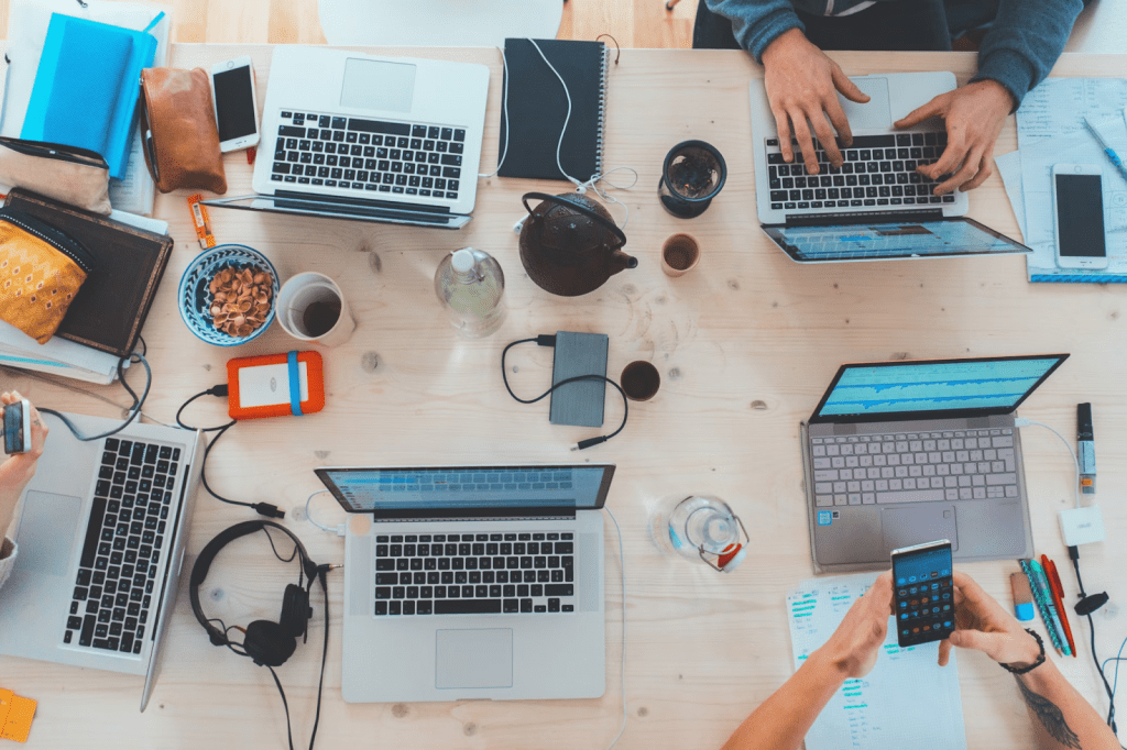 People sitting down near table with assorted laptop computers doing market research