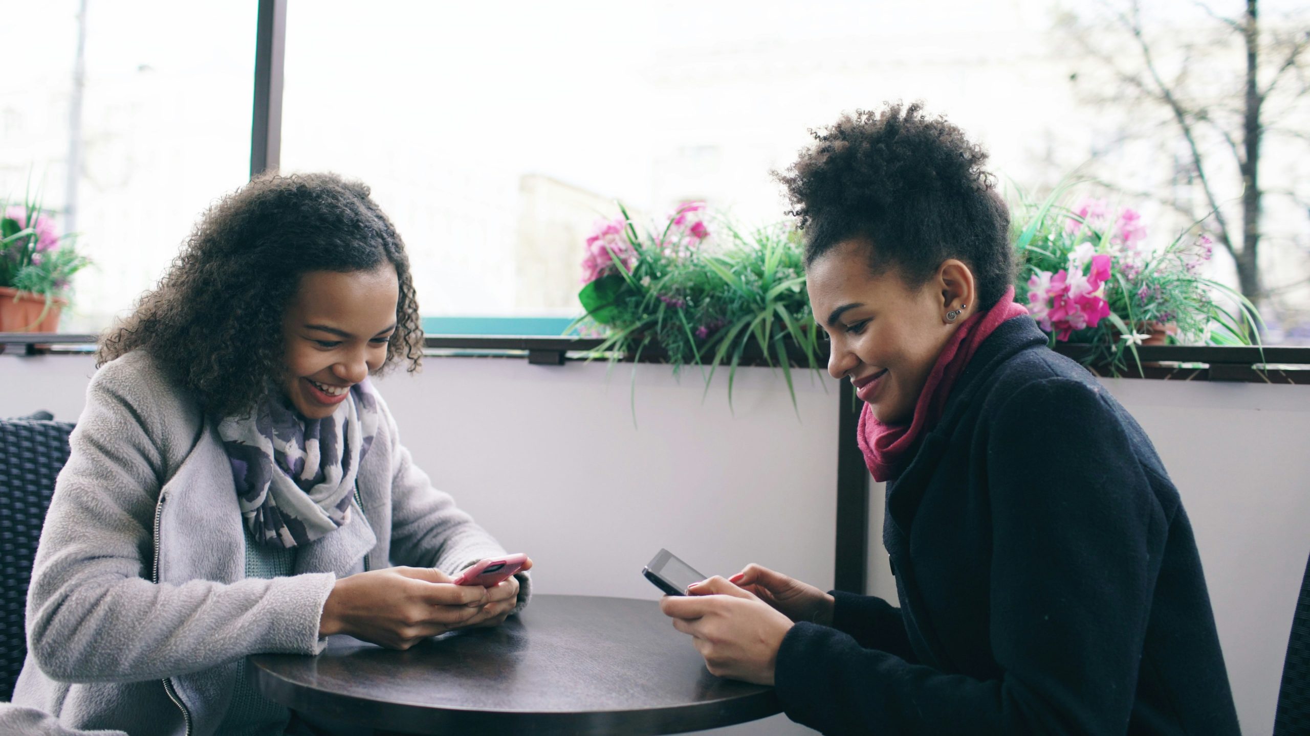 Two people completing a survey on their phones at a café table