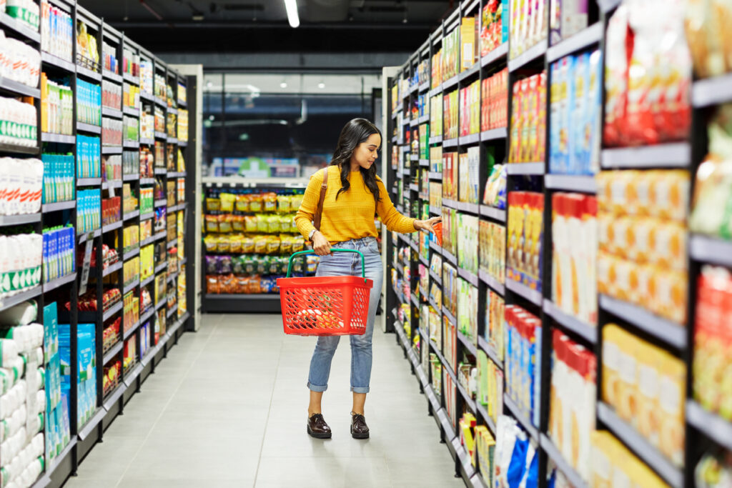 Women in a grocery store selecting a product off the shelf