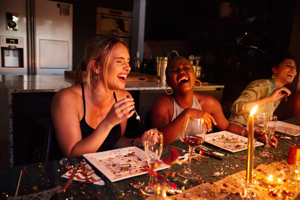 A group of Gen Z women socialise together while drinking alcohol at a celebration.