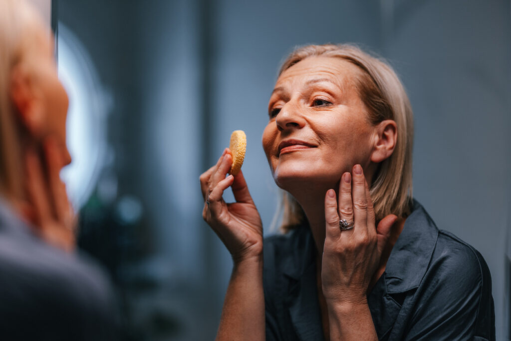 An older women applies skincare products to her face