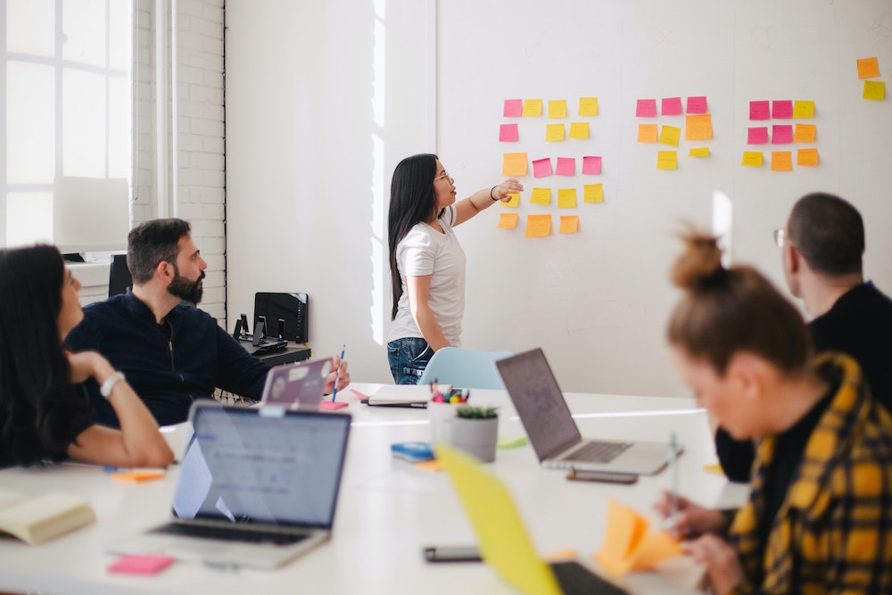 A healthcare marketer in a meeting placing post-it notes on a wall.