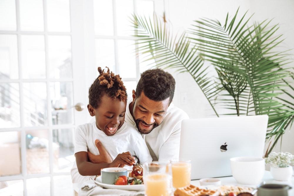 Father and son eating breakfast infront of a laptop