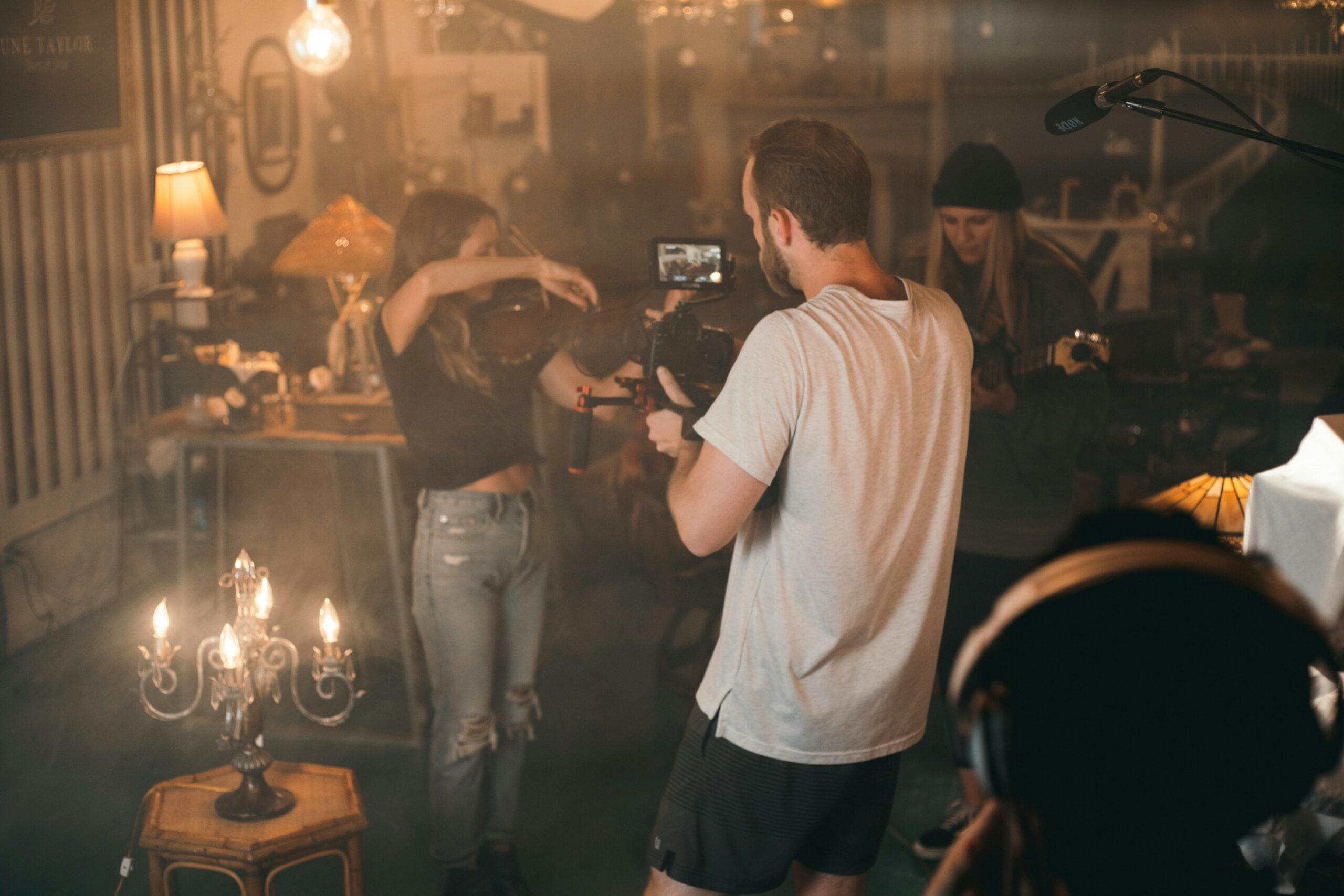 Videographer filming an in a dimly lit indoor set.