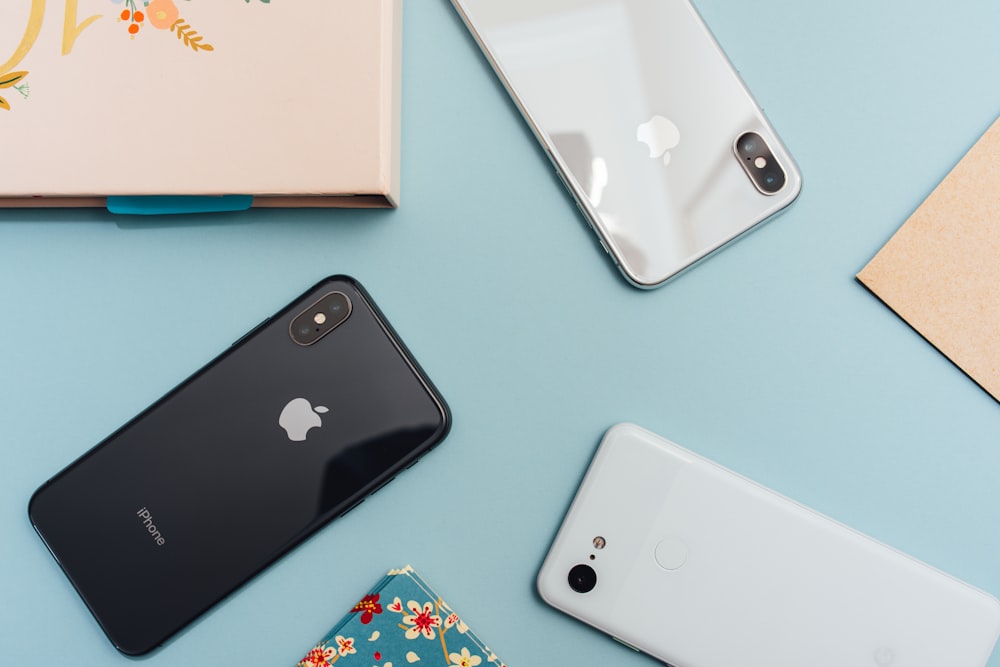 Flat lay of three smartphones and folders on a light blue background.