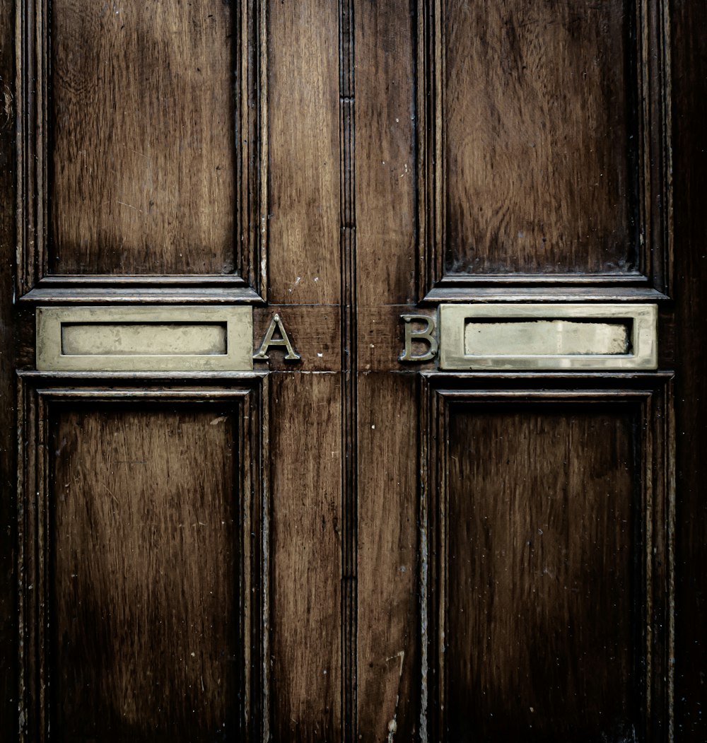 Close-up of a wooden door featuring two brass letterboxes labeled A and B.