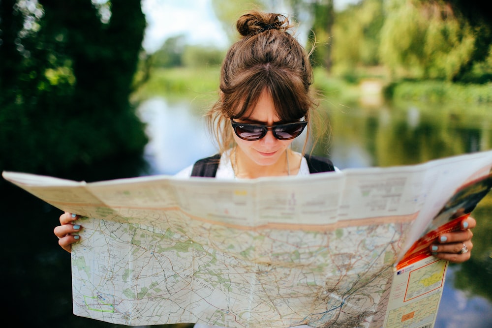 A woman wearing sunglasses and reading a map