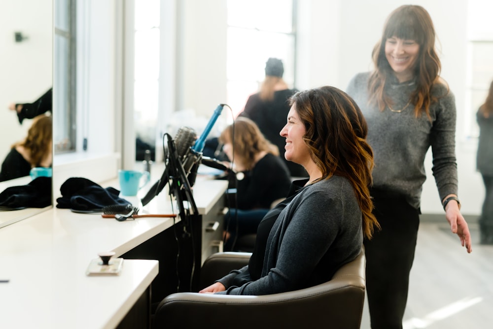 A smiling woman sits down at the hair salon.