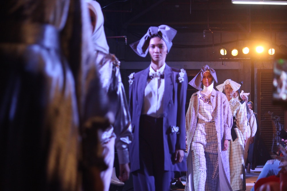 Fashion models walking on a runway in headscarves and long flowing clothes.