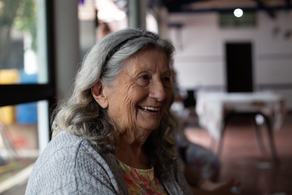 An old woman sitting in a healthcare clinic and smiling.