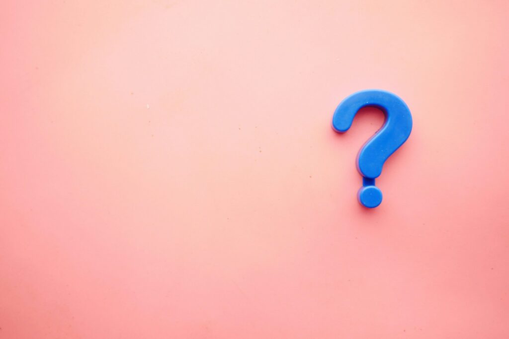 Blue question mark on a pink background representing biased survey questions and the importance of clear, neutral wording.