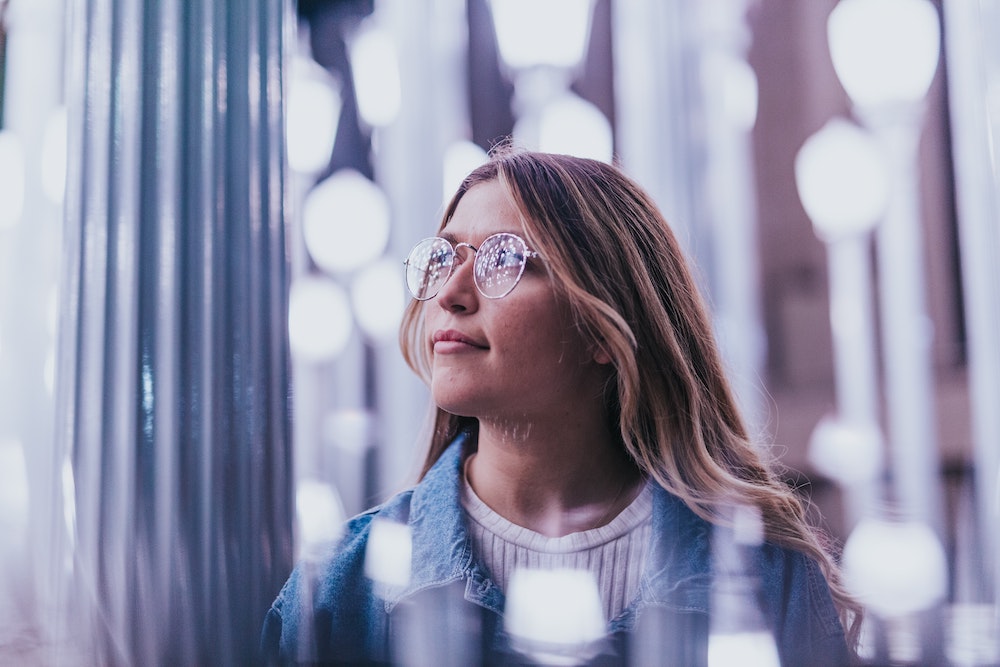 A woman with glasses looking into the distance