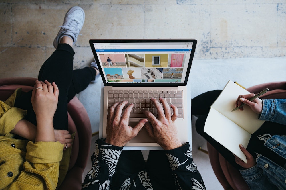 Three people sitting together looking at photographs on a laptop